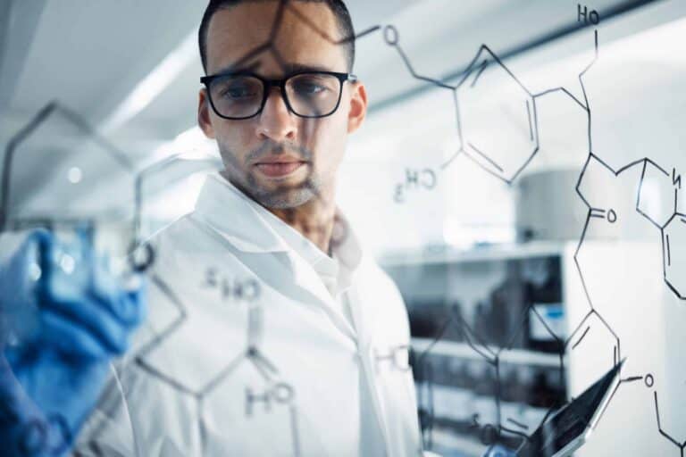 shot of a young scientist solving equations on a glass screen in a laboratory